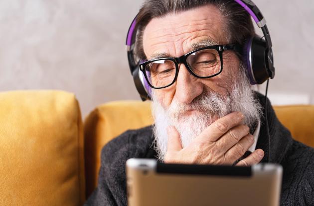 Ældre mand lytter med headset og tablet